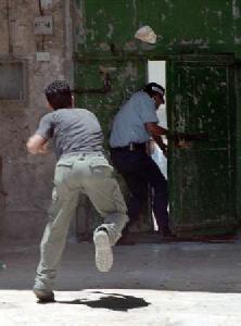 Араб бросает камень  в вооруженного израильского полицейского,  а тот убегает